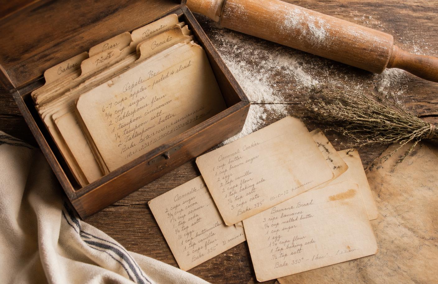 Open wooden recipe box with handwritten yellowed recipe cards on a farmhouse table
